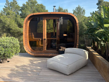 ICON 300 Kube i termotre på en terrasse, med helglassfront og dør, vedfyrt ovn og pipe synlig gjennom glasset